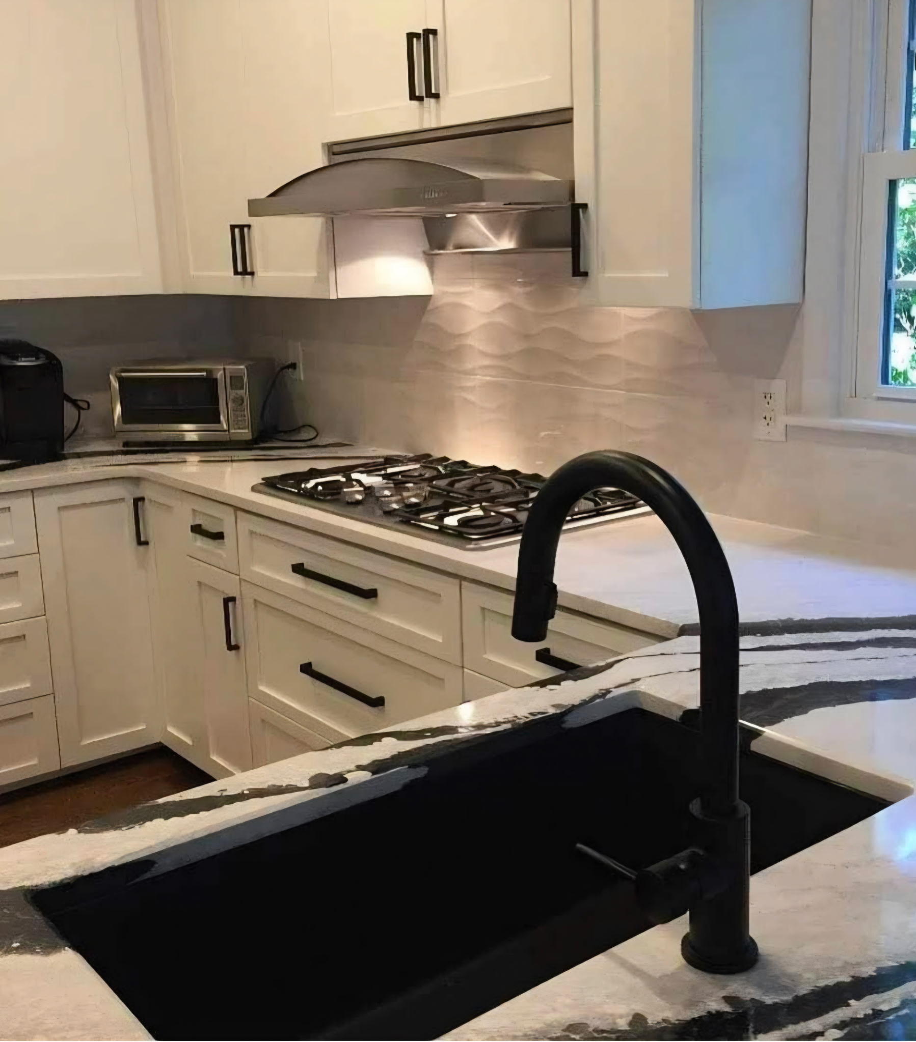 Dramatic black and white quartzite countertop with wave tile backsplash
