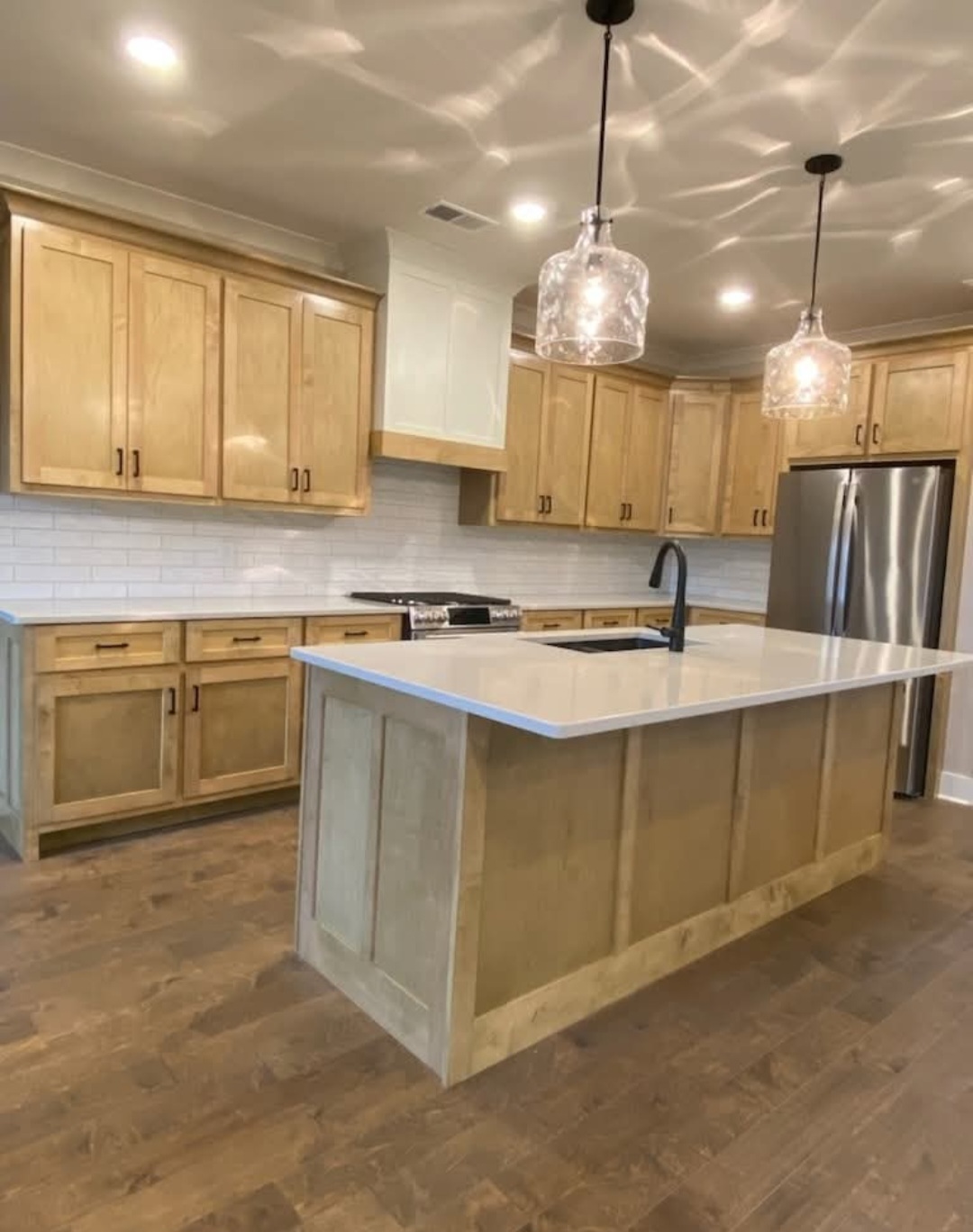 Natural wood kitchen with white quartz island and subway tile backsplash